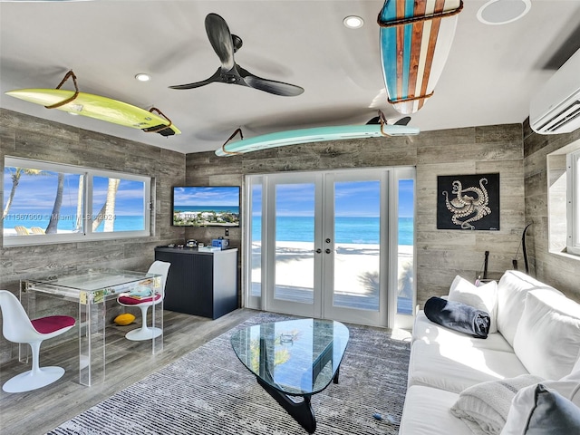 living room with french doors, plenty of natural light, tile walls, and a water view