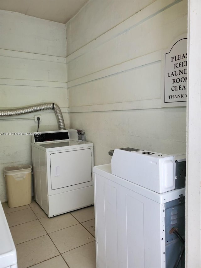 clothes washing area featuring hookup for an electric dryer, light tile floors, and washer and clothes dryer