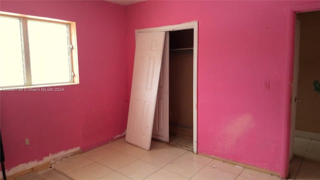 unfurnished bedroom with light tile patterned flooring and a closet