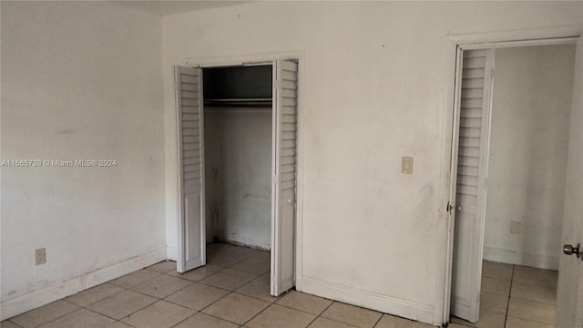 unfurnished bedroom with light tile patterned floors and a closet