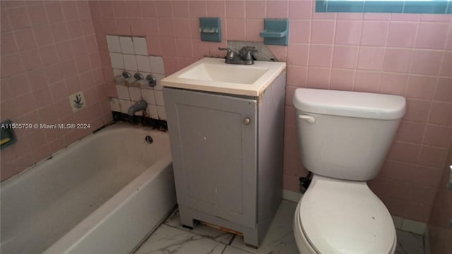 bathroom featuring vanity, toilet, tile walls, and a washtub