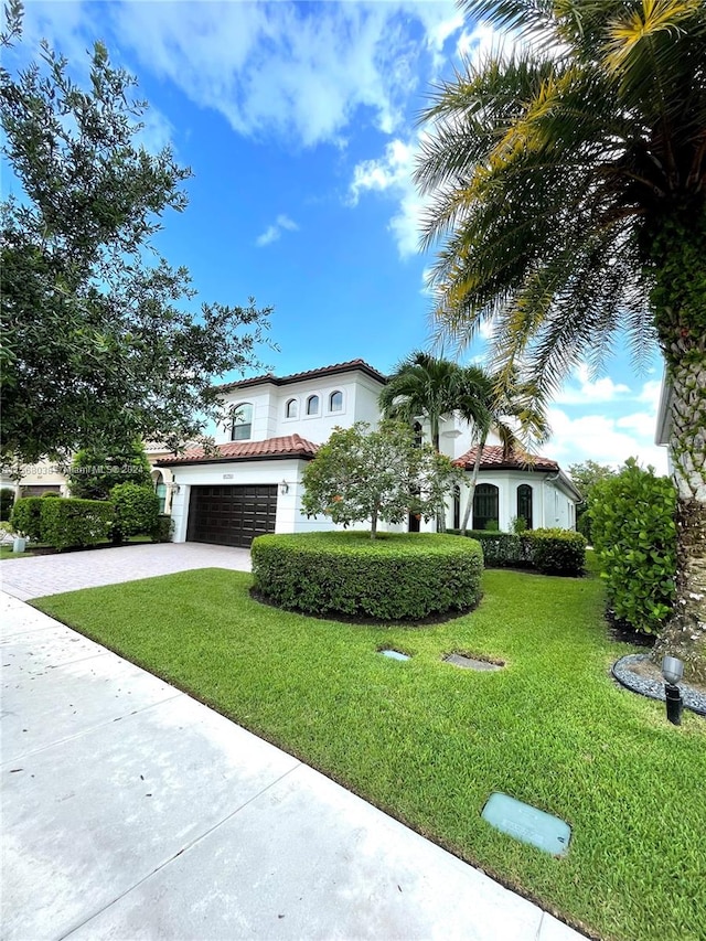 mediterranean / spanish home featuring a front yard and a garage