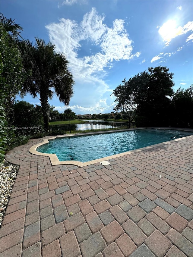 view of swimming pool with a water view and a patio area