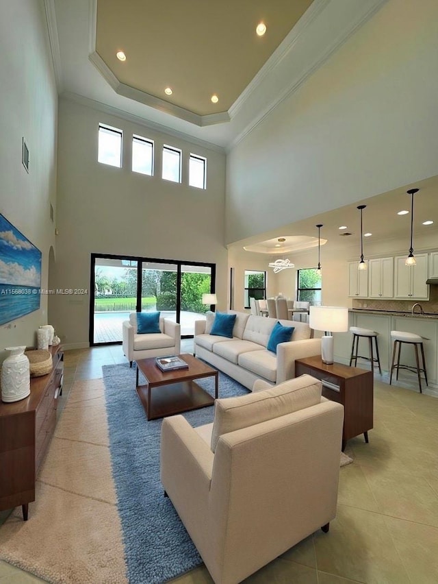 living room featuring ornamental molding, a high ceiling, a raised ceiling, and light tile patterned floors