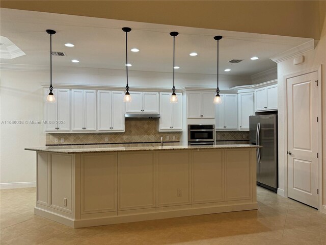 kitchen with appliances with stainless steel finishes, white cabinets, decorative light fixtures, and an island with sink