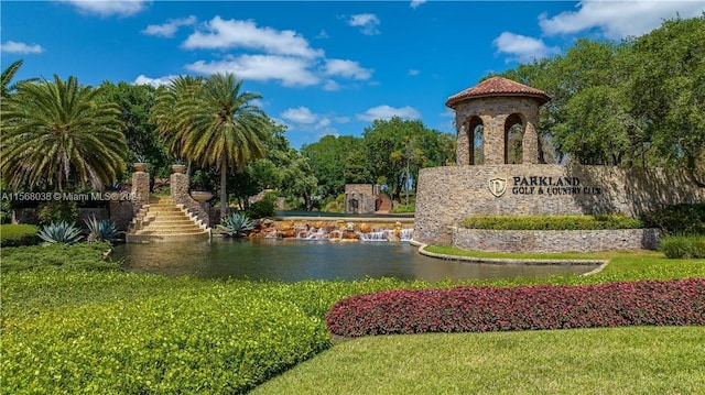 community / neighborhood sign featuring a water view and a lawn