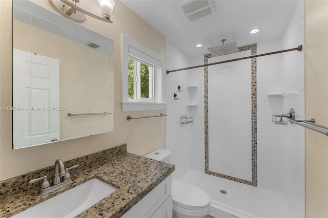 bathroom with vanity, toilet, and a tile shower