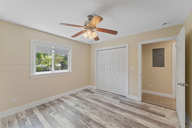 unfurnished bedroom featuring a closet, electric panel, light hardwood / wood-style flooring, and ceiling fan