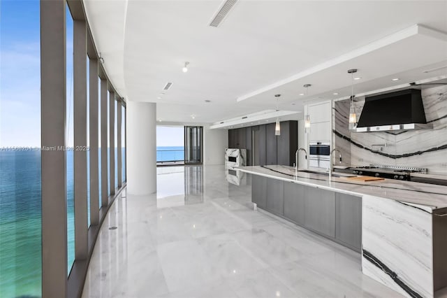 kitchen with light stone countertops, pendant lighting, visible vents, and modern cabinets