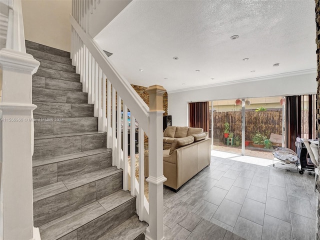 stairs with a textured ceiling, ornate columns, crown molding, and tile floors