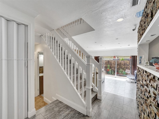 stairs with a textured ceiling and light tile floors