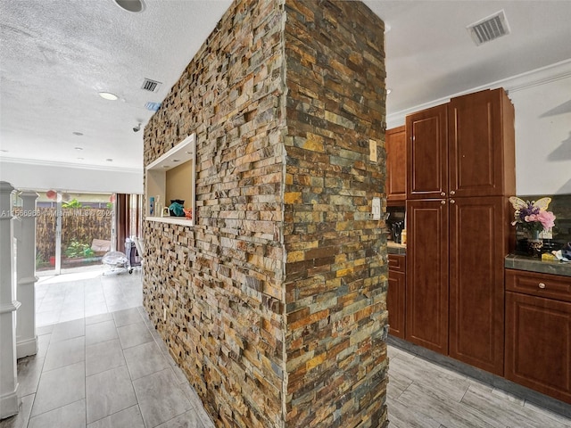 corridor featuring ornamental molding, light tile floors, and a textured ceiling