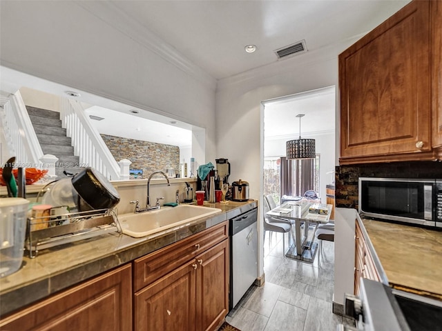 kitchen with decorative light fixtures, appliances with stainless steel finishes, backsplash, sink, and ornamental molding