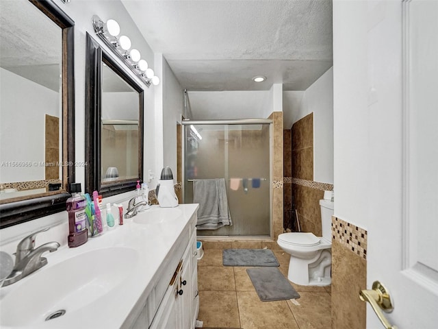 bathroom featuring walk in shower, large vanity, tile flooring, dual sinks, and toilet