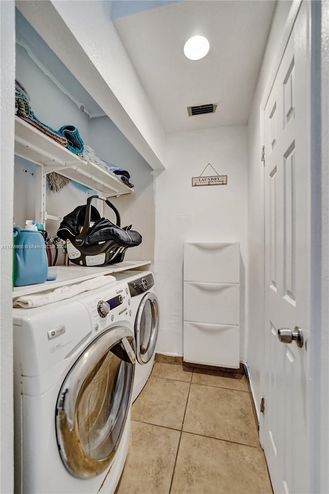 laundry area featuring washer and dryer and light tile floors