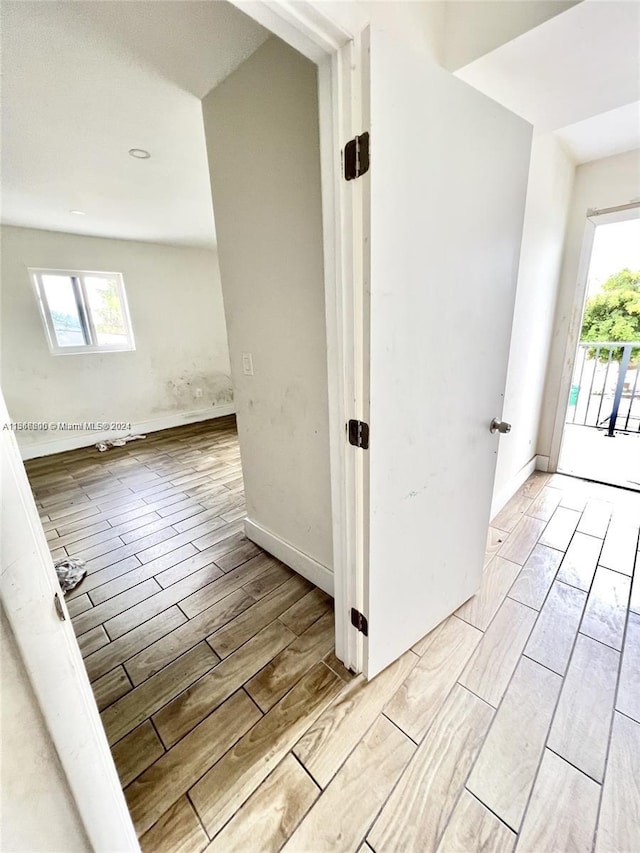 corridor with light hardwood / wood-style floors, a baseboard radiator, and a skylight