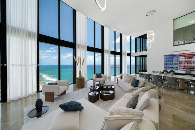 living room with a wall of windows, a water view, and a high ceiling