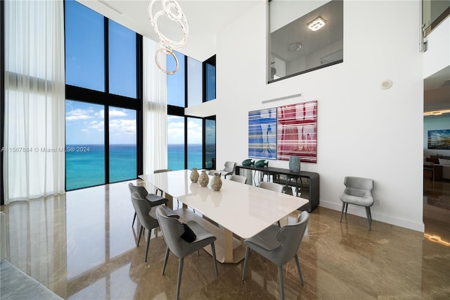 tiled dining area with expansive windows, a water view, a towering ceiling, and a chandelier