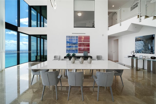 dining room with expansive windows, tile floors, a towering ceiling, and a water view