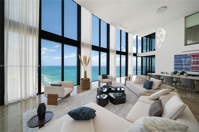 living room featuring floor to ceiling windows, a high ceiling, and a water view