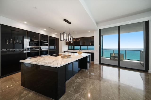 kitchen featuring hanging light fixtures, light stone countertops, black appliances, a water view, and a kitchen island