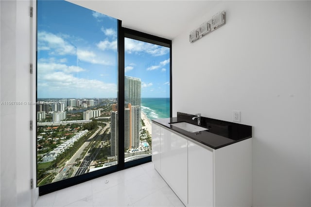 clothes washing area with plenty of natural light, a water view, sink, and light tile flooring