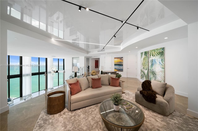 living room with expansive windows, track lighting, a tray ceiling, and a towering ceiling