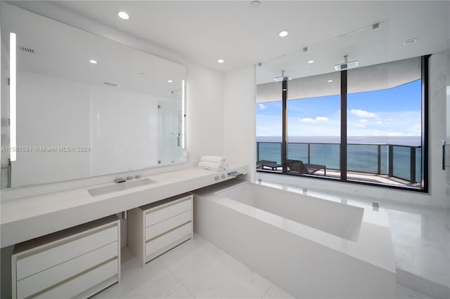 bathroom featuring a water view, vanity, tile floors, and a bath