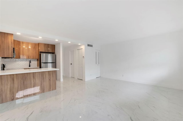 kitchen with backsplash, sink, light tile floors, and stainless steel fridge