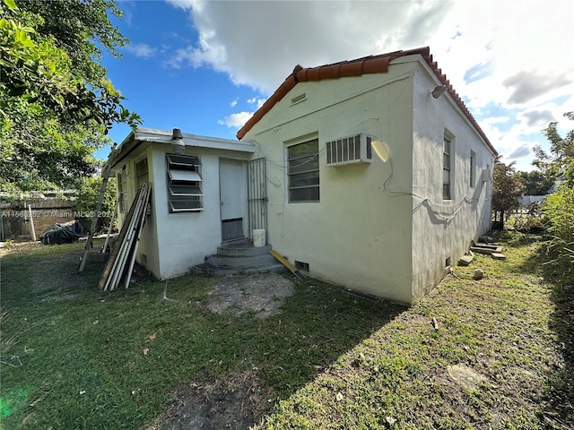 rear view of property featuring a yard and a wall unit AC