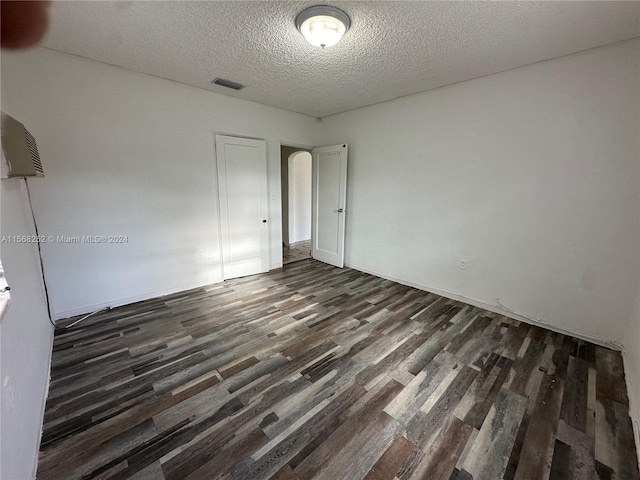 spare room featuring dark hardwood / wood-style flooring and a textured ceiling