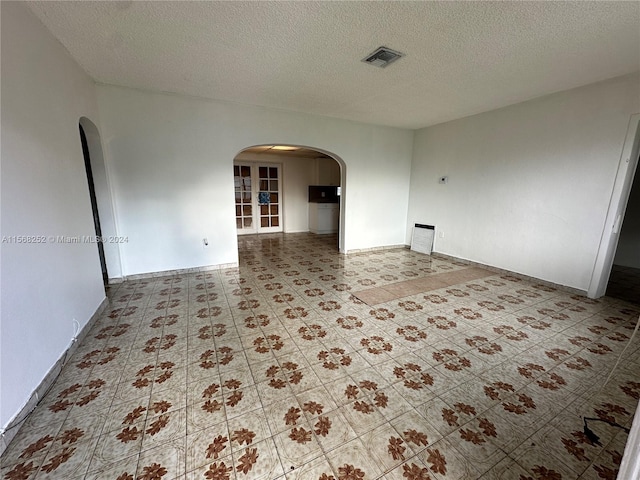 tiled empty room with a textured ceiling