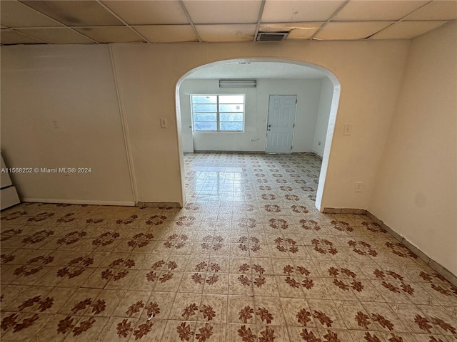 tiled spare room featuring a paneled ceiling