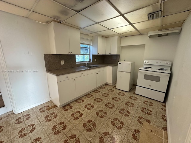 kitchen featuring a paneled ceiling, light tile floors, white appliances, backsplash, and white cabinetry