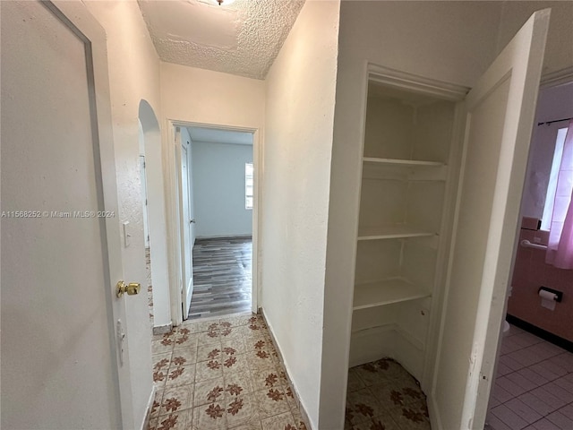 hall with a textured ceiling and light tile floors