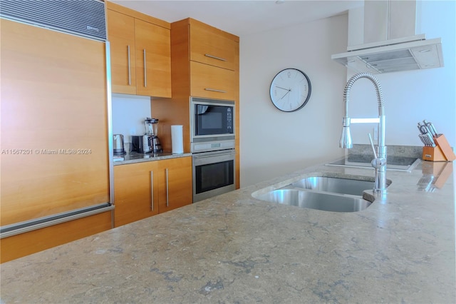 kitchen featuring oven, sink, light stone countertops, and black microwave