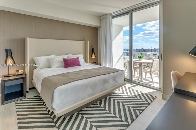 bedroom featuring light hardwood / wood-style flooring, expansive windows, and access to outside