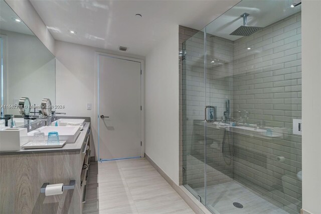 bathroom with vanity with extensive cabinet space, double sink, tile flooring, and a shower with door