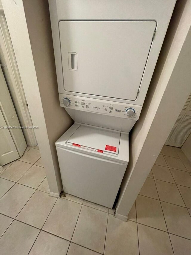 laundry room featuring stacked washer / drying machine and light tile patterned floors