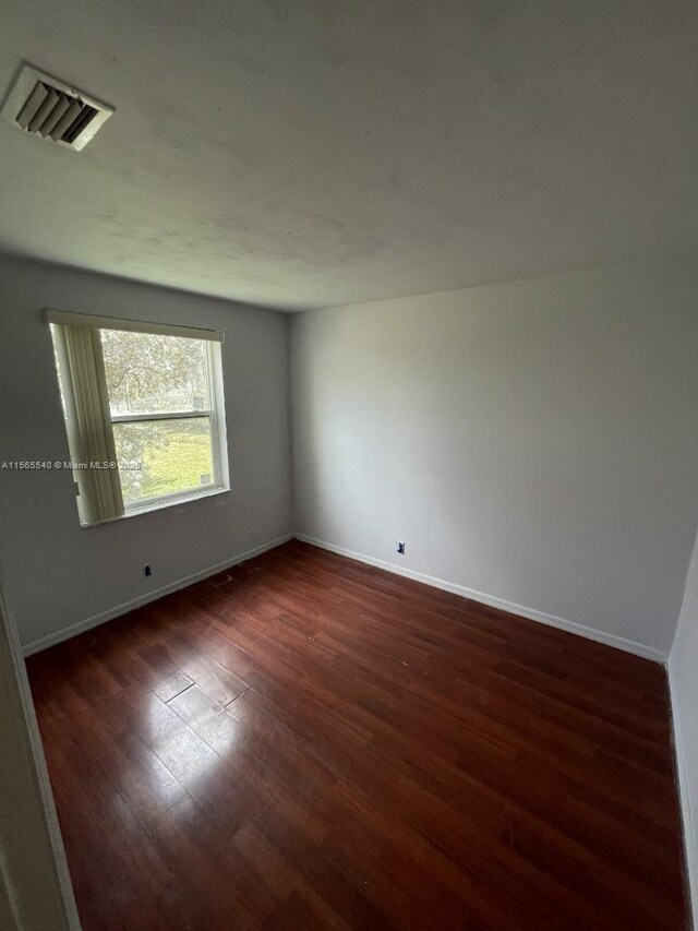 empty room with dark hardwood / wood-style flooring