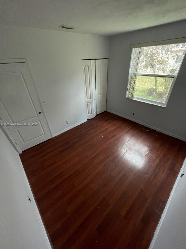 unfurnished bedroom with dark hardwood / wood-style flooring and a closet