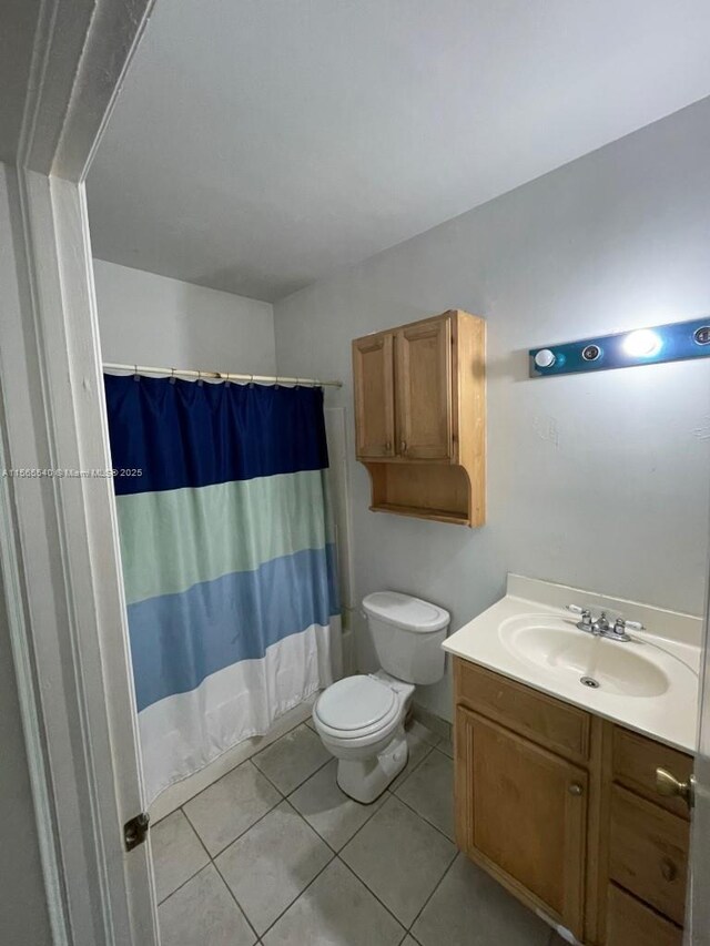 bathroom with tile patterned flooring, vanity, curtained shower, and toilet