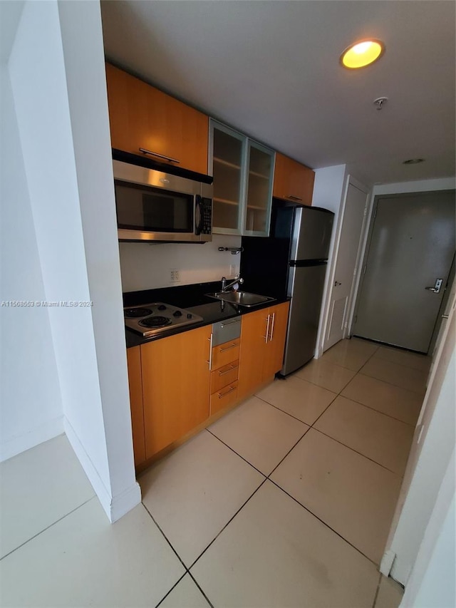 kitchen with stainless steel appliances, sink, and light tile flooring