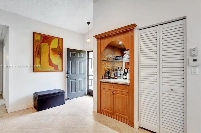 hallway with a textured ceiling and light tile floors