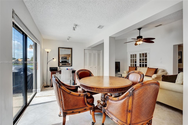 dining area featuring ceiling fan, french doors, a textured ceiling, and light tile floors