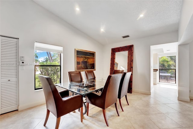 dining room featuring a textured ceiling, light tile flooring, and lofted ceiling