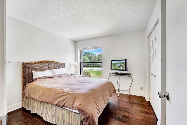 bedroom with a closet, a textured ceiling, and dark hardwood / wood-style floors