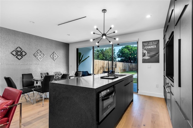 kitchen with light hardwood / wood-style flooring, a chandelier, black oven, a center island, and decorative light fixtures