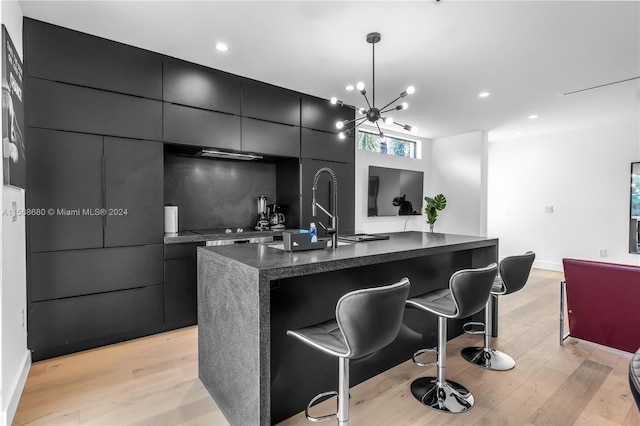 kitchen with light hardwood / wood-style flooring, a breakfast bar, backsplash, decorative light fixtures, and a spacious island