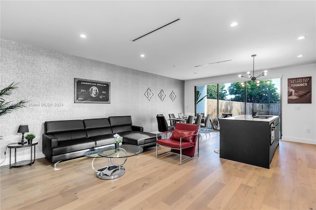 living room with a notable chandelier, light hardwood / wood-style flooring, and sink